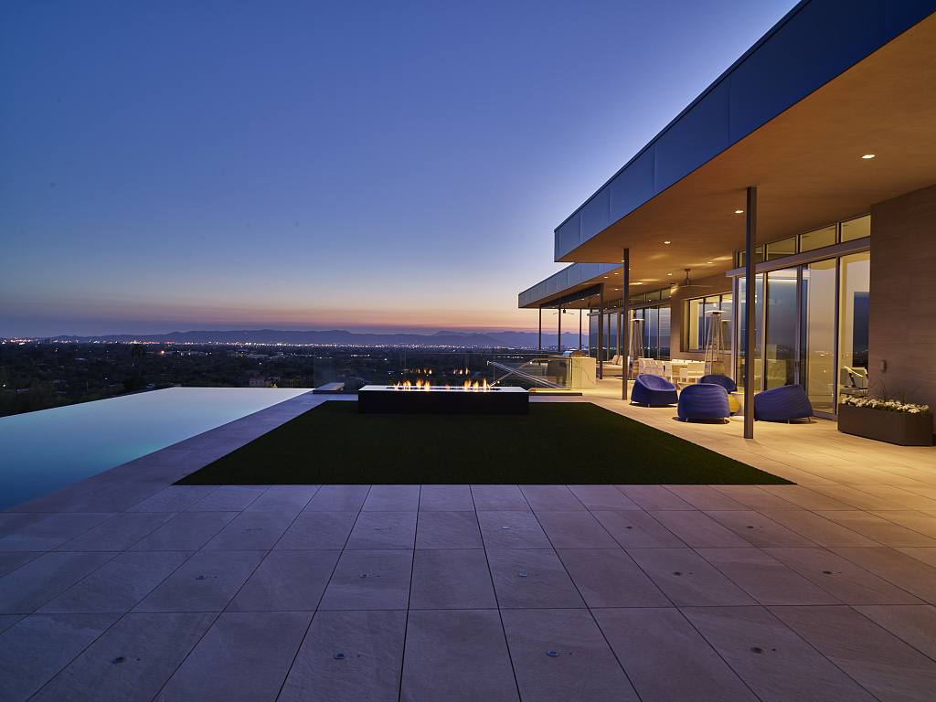 A modern home with an infinity pool and an expansive valley view at dusk
